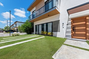 Ein modernes Wohnhaus mit zwei Etagen, einem gepflegten Rasen, einer Auffahrt und einer Garage.