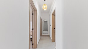 En gang med trædøre, et spejl og en hængende lampe.
