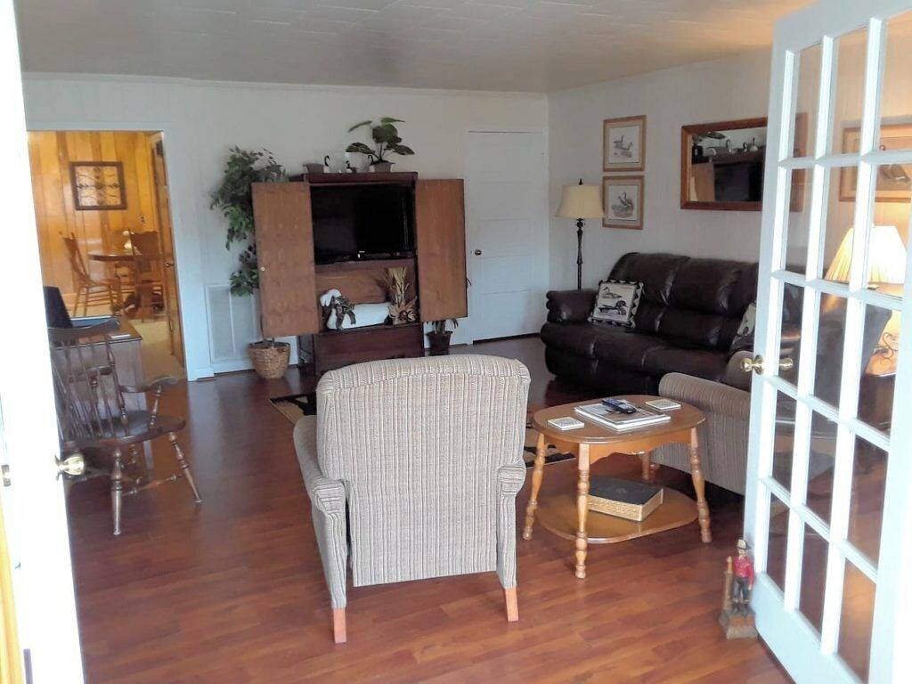 Ein Wohnzimmer mit einer Couch, einem Sessel, einem Couchtisch und einem Fernseher auf einer Holzkommode.