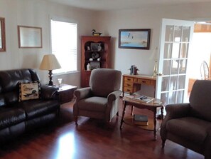 A living room with a leather sofa, a brown armchair, a wooden coffee table, and a bookshelf. - Currituck Waterfowl Homestead – Pond, Club Room, 10 minutes to Outer Banks (Powells Point)