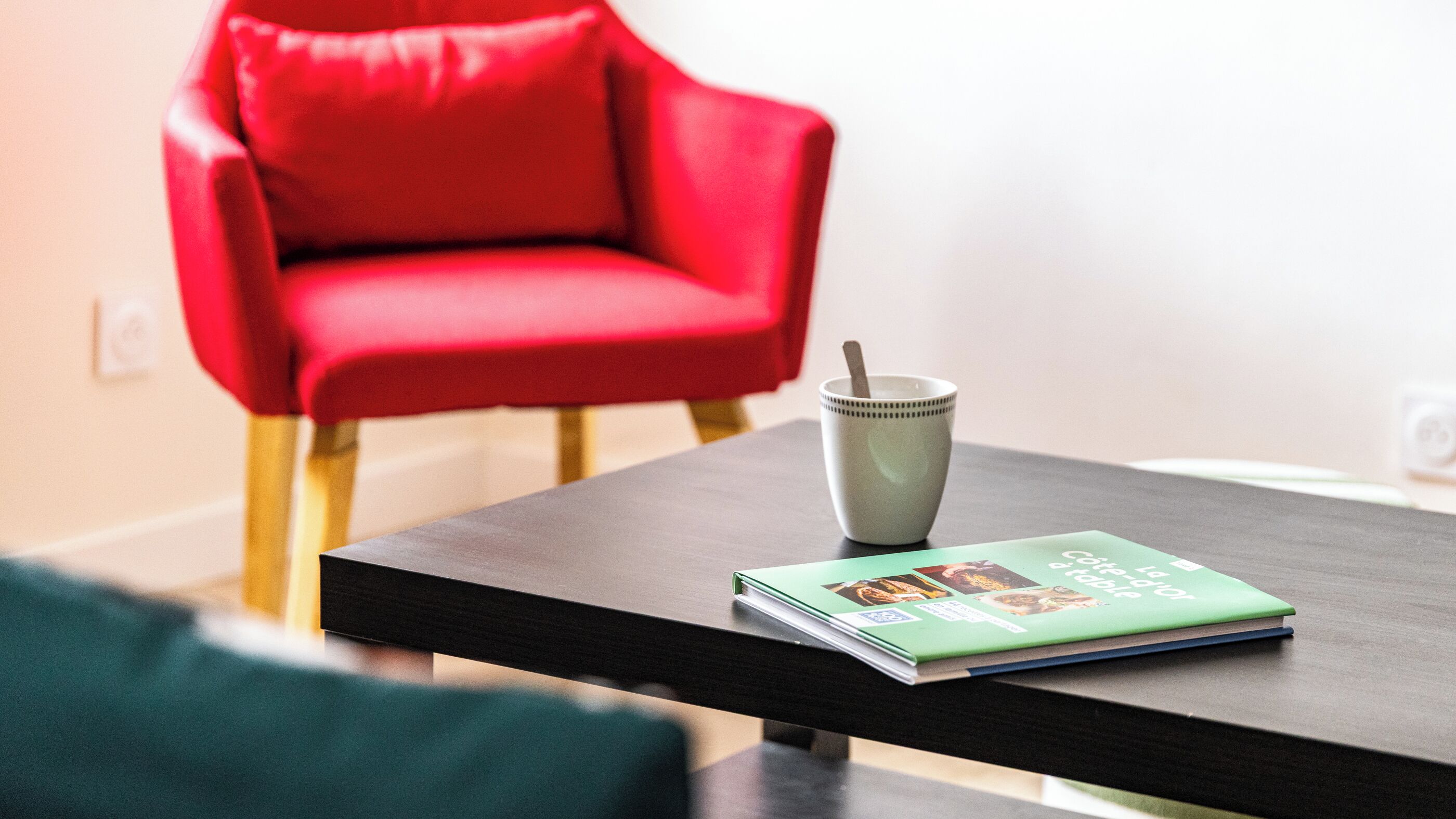 A modern living room with a red chair, a coffee table, and a book.