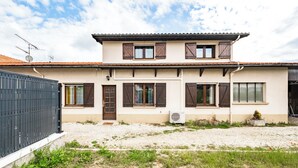 A two-story building with a tiled roof, multiple windows with shutters, and a gravel driveway. - The Marsannay Getaway | Air-Conditioned Family Home | Route des Grands Crus (Marsannay-la-Côte)