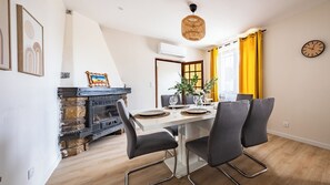 A dining area with a table set for four, a fireplace, and a clock on the wall.