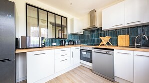 A modern kitchen with white cabinets, a stainless steel dishwasher, and a wooden countertop.