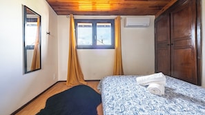 Un dormitorio con cama, ventana con cortinas, espejo y armario de madera.