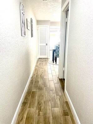 Ein Flur mit Holzboden, weißen Wänden und einer geschlossenen Tür am Ende.