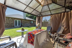 An outdoor patio with a table, chairs, and a covered area. - Fall Family Stay | 3BR w/ Fenced Yard, NW SA (San Antonio)