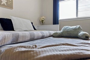 Ein ordentlich bezogenes Bett mit gesteppter Bettdecke, Kissen und Stofftier.