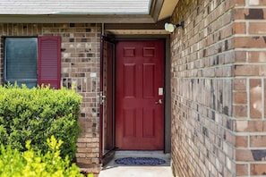 A red door with a mailbox and a doormat on a brick house. - Fall Family Stay | 3BR w/ Fenced Yard, NW SA (San Antonio)