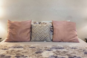 A bed with a floral bedspread and three pillows. - Fall Family Stay | 3BR w/ Fenced Yard, NW SA (San Antonio)