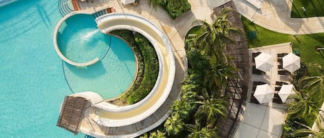 A resort with a large circular pool, palm trees, and outdoor seating areas.