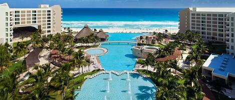 Ein Resort mit einem zentralen Pool, direkt am Strand und mehreren Gebäuden.