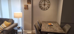 A living room with a sofa, a side table with a lamp, and a dining area with a table and chairs. - Cozy Central London, Zone 1 Apartment, Sleeps 5 (London)