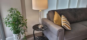 A modern living room with a grey sofa, a floor lamp, and a potted plant. - Cozy Central London, Zone 1 Apartment, Sleeps 5 (London)