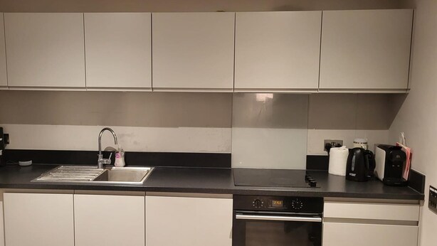 Cozinha moderna com armários brancos, bancada preta, lava-louças embutida e cafeteira.