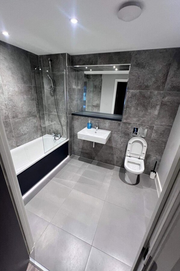Ein modernes Badezimmer mit einer gläsernen Dusche, einem weißen Waschbecken und einer Toilette.