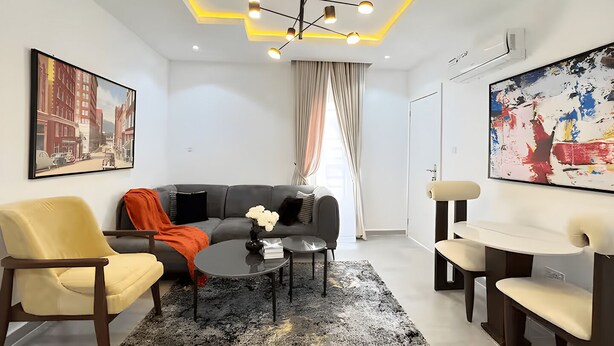 Un salon moderne avec un canapé, des fauteuils, une table basse et des œuvres d’art accrochées aux murs.
