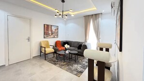 Un salon moderne avec un canapé, des fauteuils, une table basse et un tableau au mur.