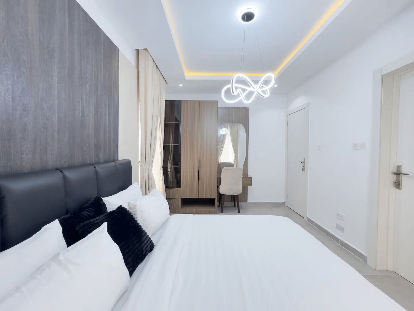 Ein modernes Schlafzimmer mit einem großen Bett, einem Schreibtisch und einem Kleiderschrank.