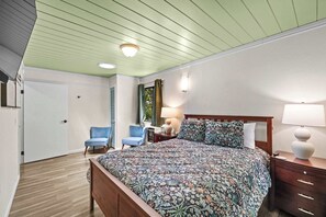 Ein Schlafzimmer mit einem hölzernen Bett, einem Nachttisch, einer Lampe und einem Sessel.
