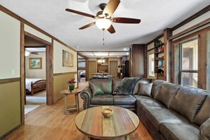 A spacious living room with a large leather sofa, a round wooden coffee table, and a ceiling fan. - Cozy Smoky Mountain Home 3BR/2BA walking distance from the Pigeon Forge Parkway (Pigeon Forge)