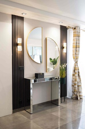 A modern bathroom with a vanity, a large mirror, and a potted plant.
