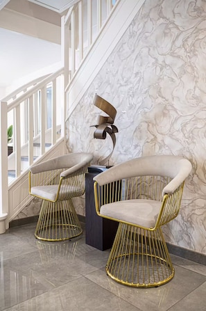 A staircase with a marble wall, two gold-framed chairs with white cushions, and a modern sculpture. - Charming luxury villa near Disneyland Paris. 6 bedrooms. Air-conditioned. Sleeps 16 (Bussy-Saint-Georges)