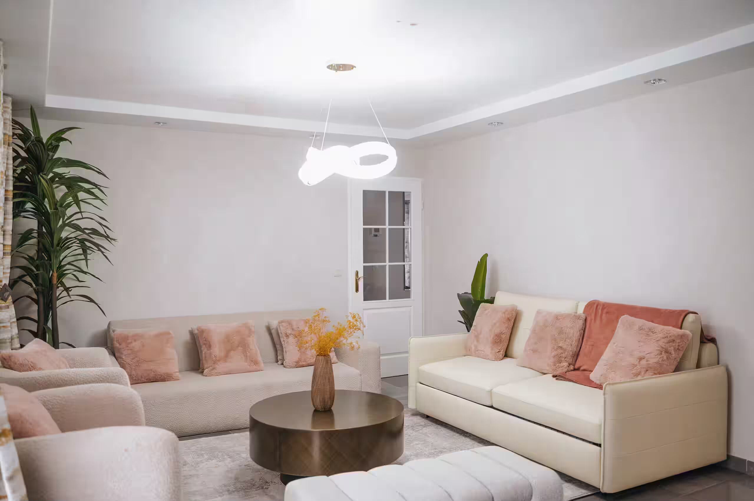 A modern living room with a sofa, a coffee table, and a hanging light fixture.