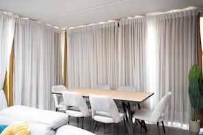 A modern dining area with a wooden table and white upholstered chairs.