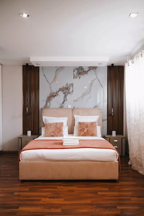 A modern bedroom with a large bed, two nightstands, a marble wall, and a wooden floor. - Charming luxury villa near Disneyland Paris. 6 bedrooms. Air-conditioned. Sleeps 16 (Bussy-Saint-Georges)