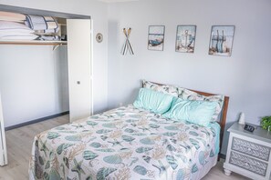 A bedroom with a bed, a bedside table with a clock, and a wall with nautical-themed artwork. - Welcome to Lazy Days Lake House. (Hayward)