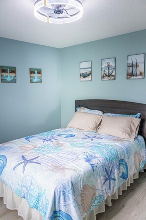 Ein Schlafzimmer mit einem Bett, einem Deckenventilator und Wandbildern.