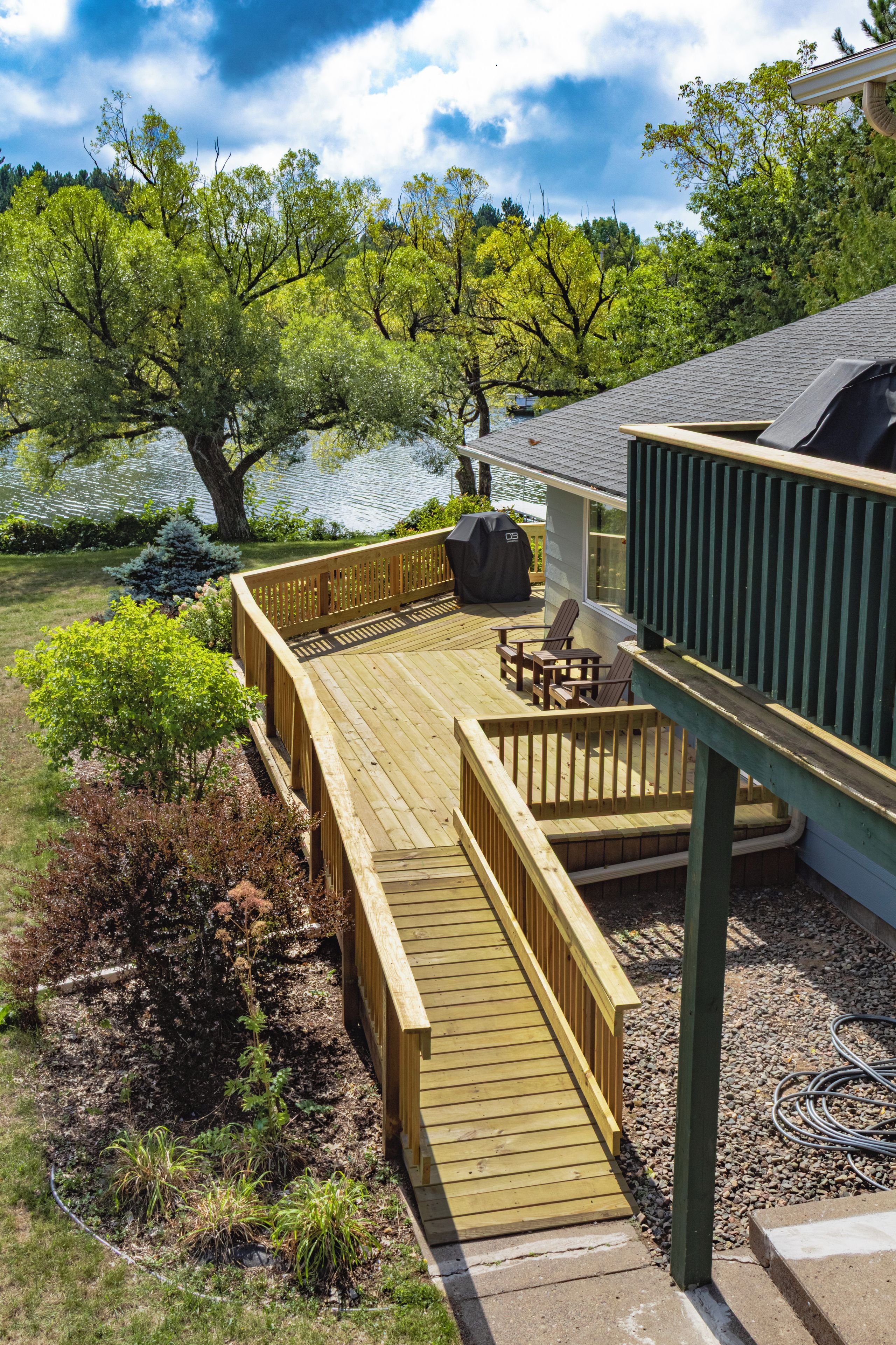 Eine Holzterrasse mit integriertem Grill, Sitzgelegenheit im Freien und Blick auf einen See.
