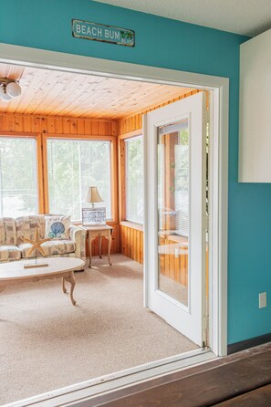 A room with a wooden ceiling, a couch, a small table, and a sign that reads 'BEACH BUM BLVD.' - Welcome to Lazy Days Lake House. (Hayward)