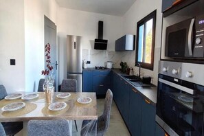 A modern kitchen with a dining area, featuring a built-in oven, microwave, and a window providing natural light. - La Caz Marmay, ocean view, heated pool, 5 bedrooms (Saint-Leu)