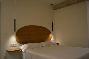 Un dormitorio con un cabecero de madera grande, una colcha blanca y una mesita de noche de madera.