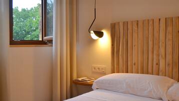 Een slaapkamer met een houten hoofdeinde, een nachtkastje met een lamp, en een raam met gordijnen.