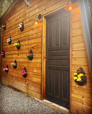 A wooden building with a dark brown door and multiple flower planters on the wall. - My eucalyptus tree cabin - a little corner of paradise. (Alfredo Wagner)