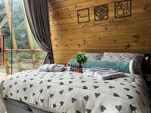 A cozy bedroom with a bed, a window with curtains, and a wooden wall with a decorative phrase. - My eucalyptus tree cabin - a little corner of paradise. (Alfredo Wagner)