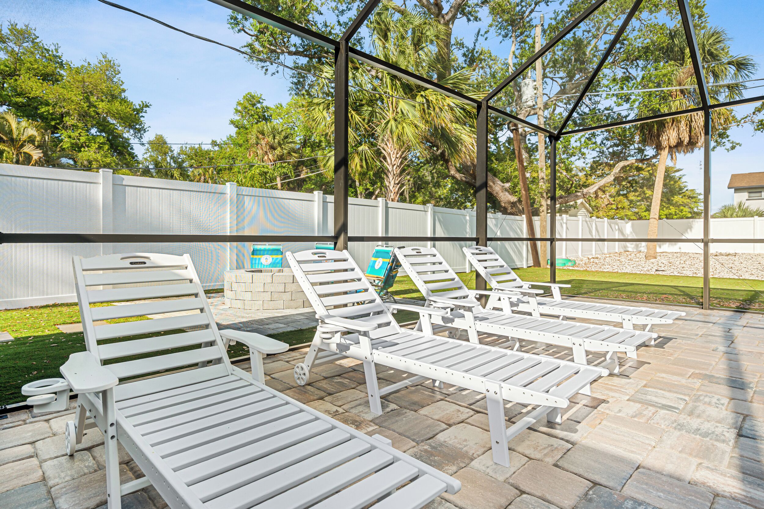 Un espace extérieur abrité, doté de chaises longues blanches et d’une terrasse en pierre.