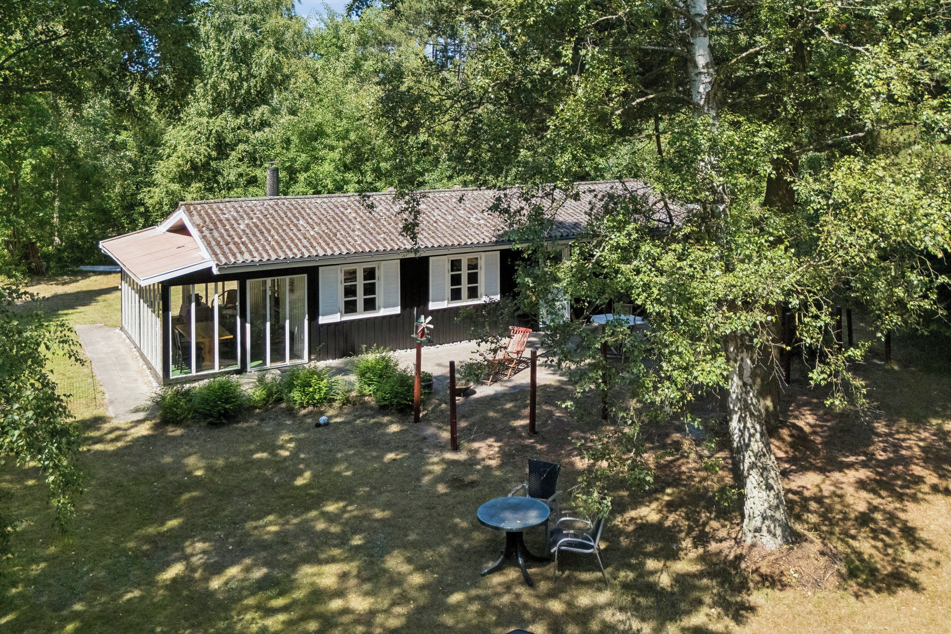 A two-story house with a balcony, surrounded by trees and a grassy yard.