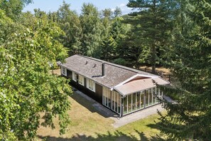 Ein zweistöckiges Haus mit überdachter Veranda und großzügigen Fenstern.