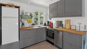 Uma cozinha moderna com armários cinza, fogão de aço inoxidável e bancada de madeira.