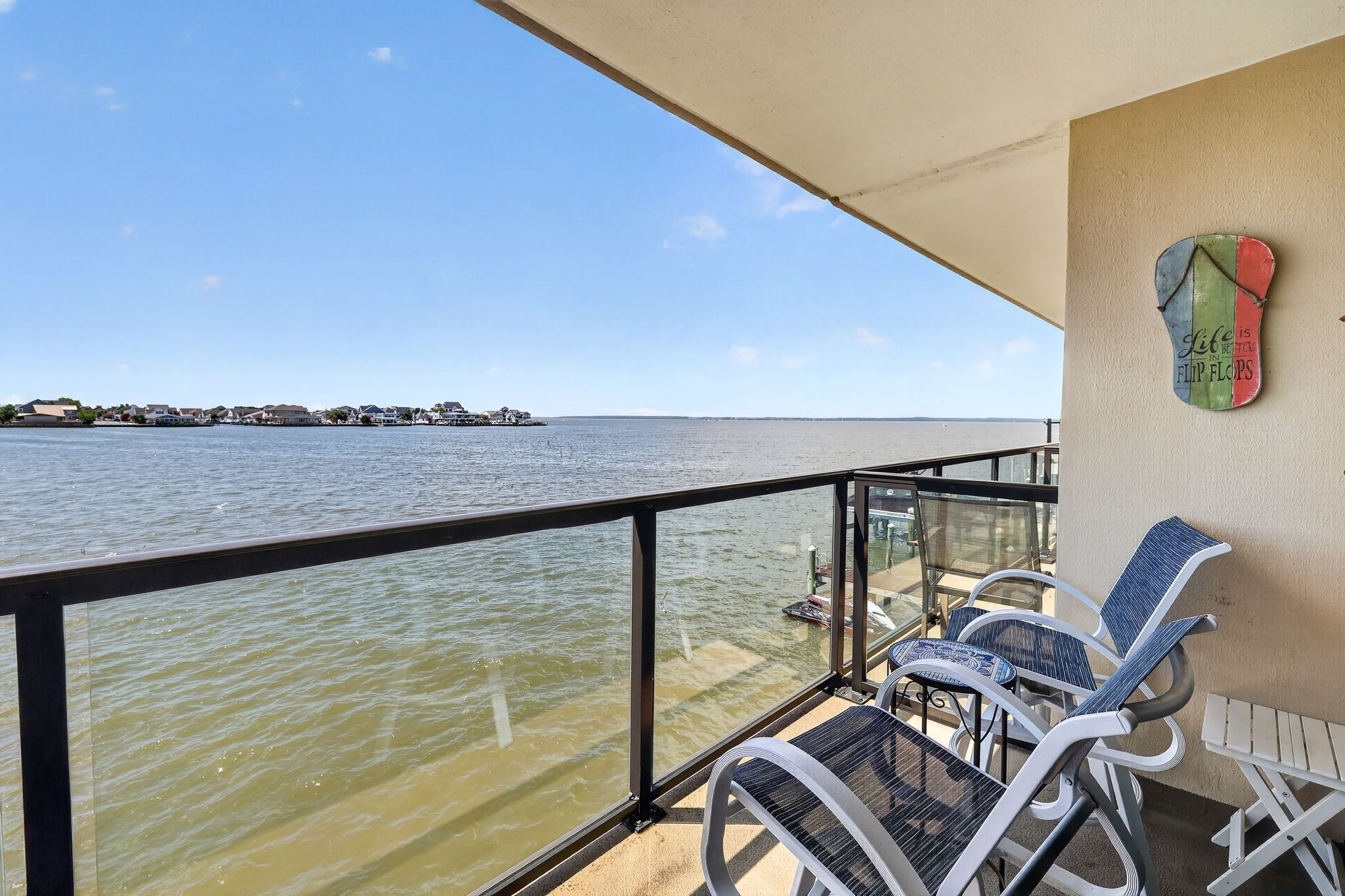 Ein Balkon mit Blick auf ruhiges Wasser, einem Geländer und zwei Stühlen.