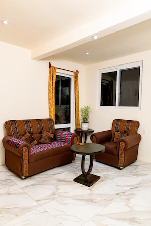 A living room with two sofas, a small table, and a potted plant.