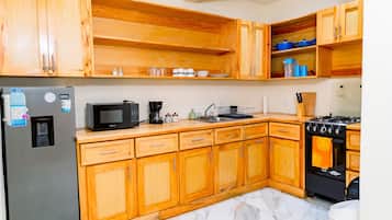 A kitchen with wooden cabinets, a stainless steel refrigerator, a microwave, a coffee maker, and a stove.