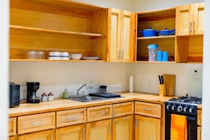 A kitchen with wooden cabinets, a stove, a sink, and various kitchen items.