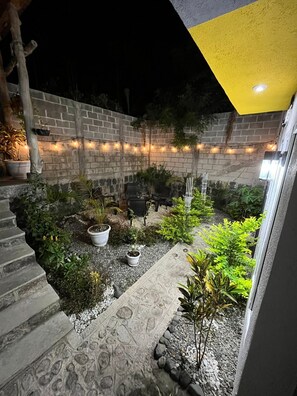 A stone pathway leading to a seating area with potted plants and a brick wall.