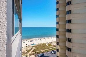 A high-rise building with a view of a beach and parking area. - Two Bedroom Beachfront Condo with Great Amenities (Ocean City)