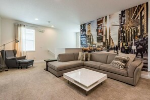 Een moderne woonkamer met een modulaire bank, een bijzettafeltje en een stadsgezicht muurschildering.